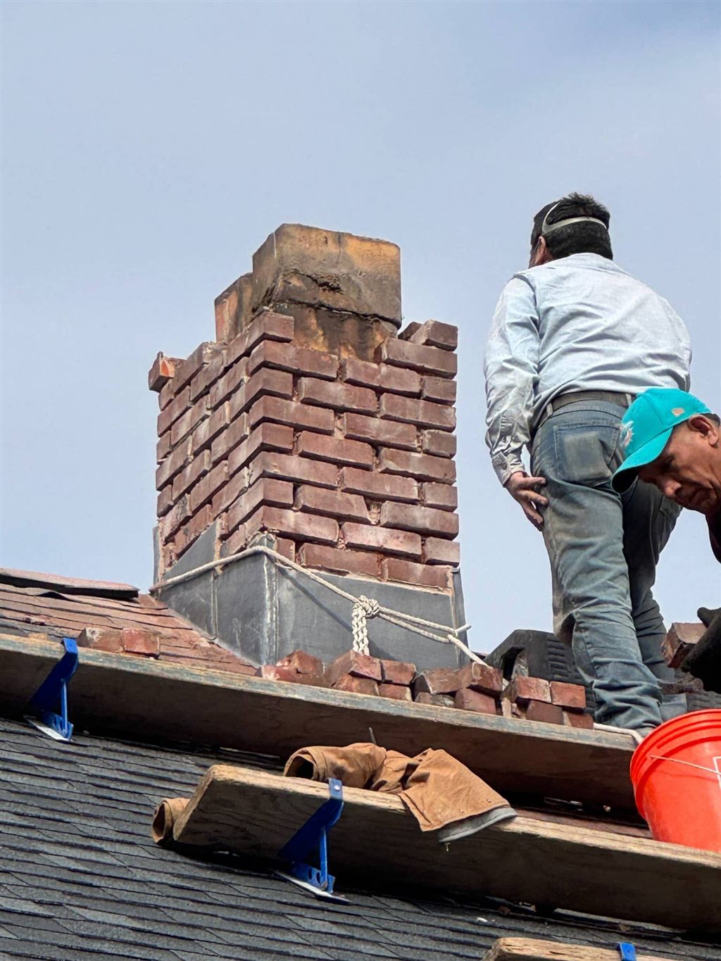 Masons rebuilding the upper courses of a brick chimney